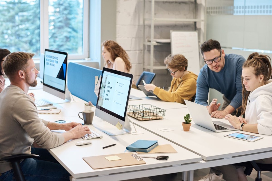 A team collaborating at their screens in a bright studio