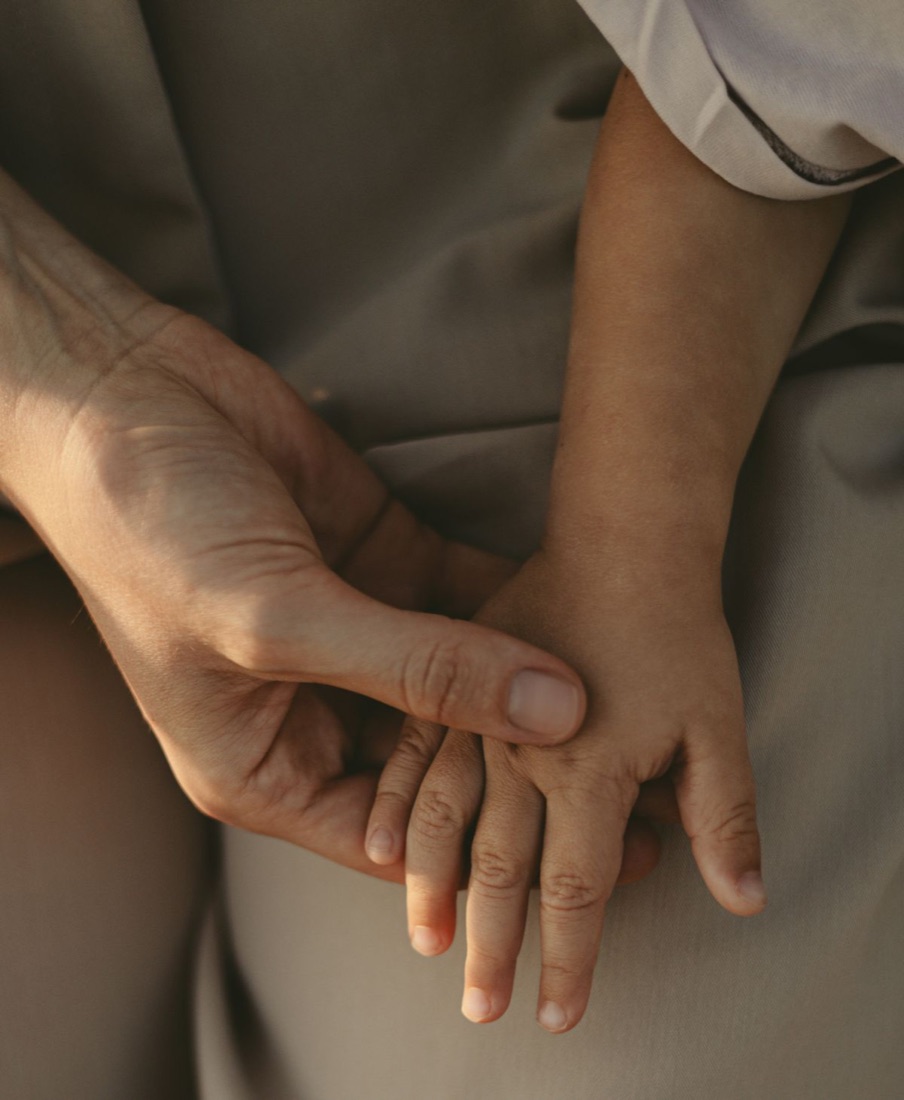 An adult’s hand and a child’s hand resting together